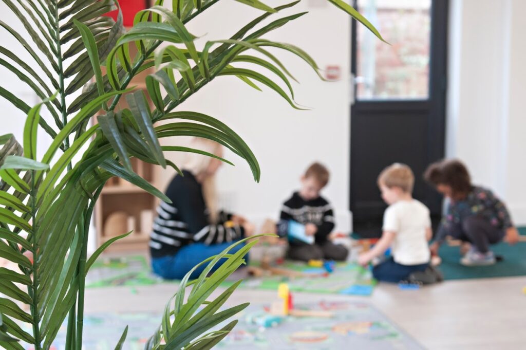 children sat playing with a manager | Ducklings Nursery